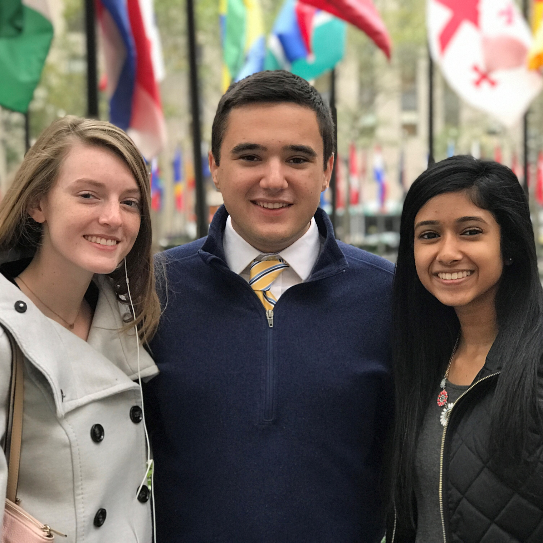 3 students smiling in front of United Nations